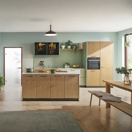 Küche mit Holzfronten, Kücheninsel, Einbaugeräten, Esstisch und Sitzbank vor grüner Wand